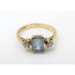 A 9ct gold ring set with central aquamarine flanked by diamonds. Ring size approx K Please Note - we