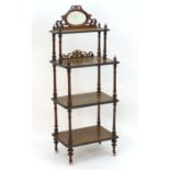 A Victorian walnut four tier whatnot with a mirrored gallery and fretwork decoration, having