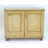 A late 19thC pine cupboard with a moulded top above two panelled doors, one with a painted porcelain