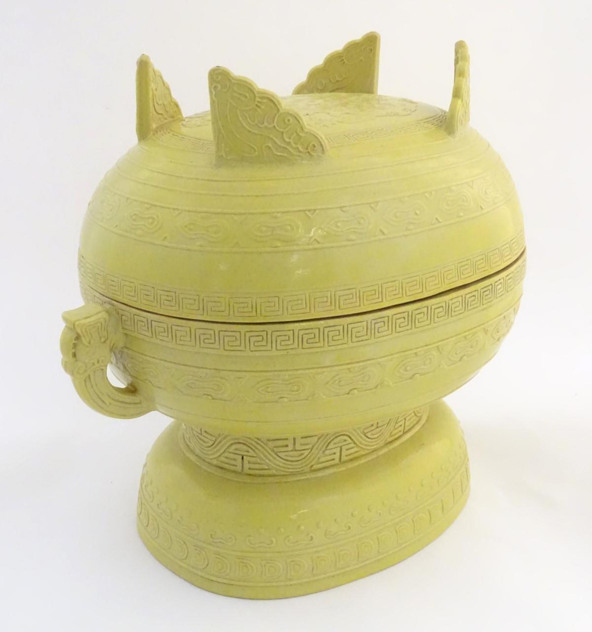A Chinese yellow ground lidded pot raised on a foot, with twin handles formed as stylised elephant