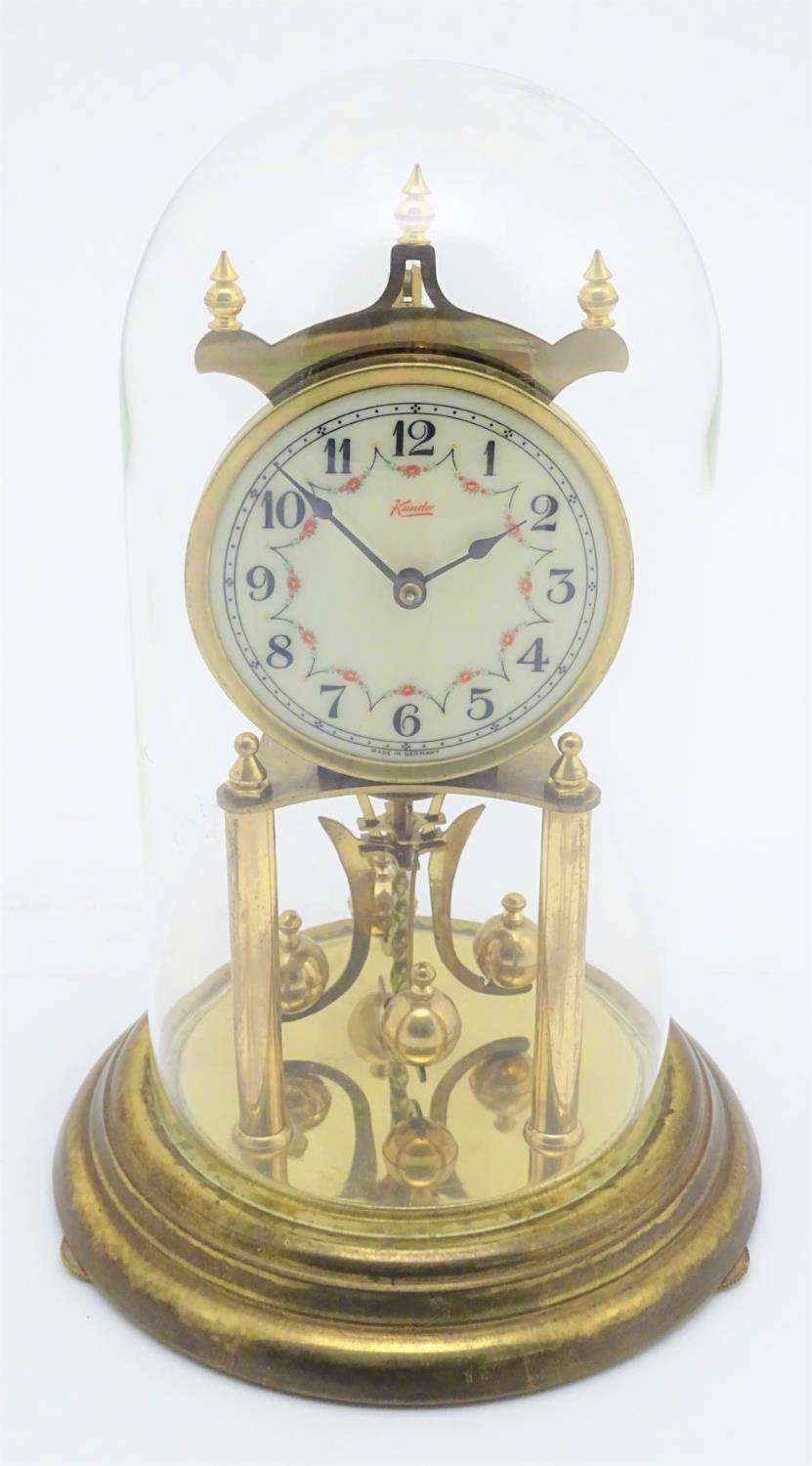 A mid 20thC 'Kundo' anniversary clock with a glass dome above a brass frame. 12" high. Please Note -