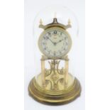 A mid 20thC 'Kundo' anniversary clock with a glass dome above a brass frame. 12" high. Please Note -