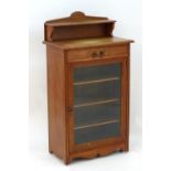 An early 20thC cabinet with a pierced and shaped upstand above a single glazed door , raised on