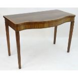 An early 19thC mahogany serving table with a serpentine shaped front, crossbanded top and having