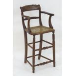 A 19thC walnut child's chair with a carved cresting rail, caned seat and standing on turned tapering