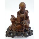 A 20thC Chinese carved sculpture depicting a seated sage / scholar reading next to a seated tiger,