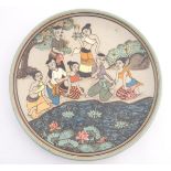 An Oriental plate, the unglazed centre decorated with a group of people in a landscape relaxing near
