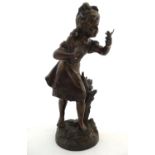 A 20thC bronze sculpture of a young girl with a bird, on a circular base with foliate detail.