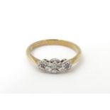 A gold ring set with trio of graduated illusion set diamonds within a platinum setting. Ring size