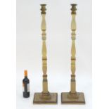 A pair of 20thC tall squared based candlesticks of carved wooden form with painted decoration and