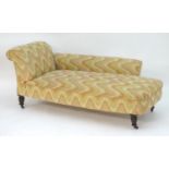 A late 19thC / early 20thC chaise lounge with scrolled backrest and arm, sprung seat and raised on