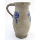 A studio pottery vase with a single handle and stylised blue flower decoration. Incised 21 under