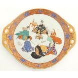 A Japanese twin handled plate with hand painted decoration depicting six seated figures with