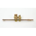 A 9ct gold bar brooch decorated with 2 perched owls set with red stone eyes. 2" wide Please Note -