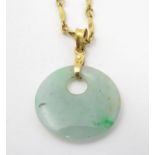 An Oriental green jade pendant on a yellow metal chain. The whole approx 25" long Please Note - we