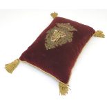 An upholstered seat cushion decorated with a Baronial coat of arms, approximately 20" long x 13"