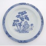 A Chinese blue and white charger decorated with a stylised landscape with trees and flowers, and a
