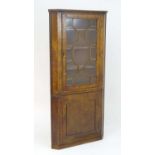 An early 19thC burr elm double corner cupboard with a moulded cornice above an astragal glazed