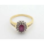 An 18ct gold ring set with central ruby bordered by diamonds with channel set diamonds to shoulders.