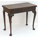 An 18thC mahogany card table / tea table with a rectangular top above cabriole legs with carved
