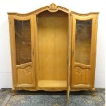 An early 20thC oak vitrine / armoire with a shell carved top and three glazed doors with carved