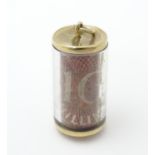 A novelty pendant charm of cylindrical form with 10 shilling note to centre and 9ct gold mounts.
