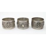 A pair of white metal napkin rings decorated with deity detail together with another with animal