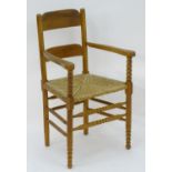 An Arts & Crafts open armchair with ladder back style backrest, envelope rush seat and having bobbin