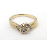 A 9ct gold ring set with central diamond flanked by diamonds to shoulders. Ring size approx J 1/2