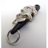 A silver gun dog whistle mount decorated with a gun dog holding a game bird, hallmarked Sheffield