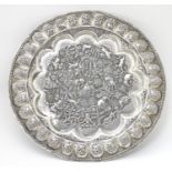 A white metal charger profusely decorated with scenes of temples, elephants, tigers, figures etc.