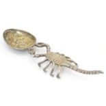A white metal spoon the handle modelled as a scorpion, the bowl decorated with deity figure.