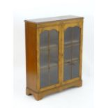 An early 20thC walnut bookcase with two astragal glazed doors opening to show three fitted shelves