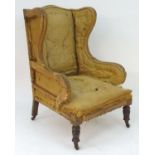 A Victorian wingback armchair standing on turned tapering front legs and sabre back legs. (Re-