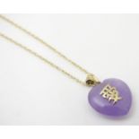 An oriental purple jade pendant with yellow metal mount and applied oriental character marks, with