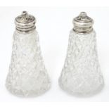 A pair of glass pepperettes with silver lids, hallmarked London 1921. Approx. 3 1/4" high Please