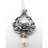 A Sterling silver pendant on a chain, the pendant with central floral detail and pearl drop. Pendant