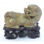 A 19thC Chinese carved soapstone Kylin Shishi upon a fitted hardwood stand with carved detail.