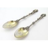 A pair of silver teaspoons with gilt bowls and ornate handles surmounted by cherubs, hallmarked