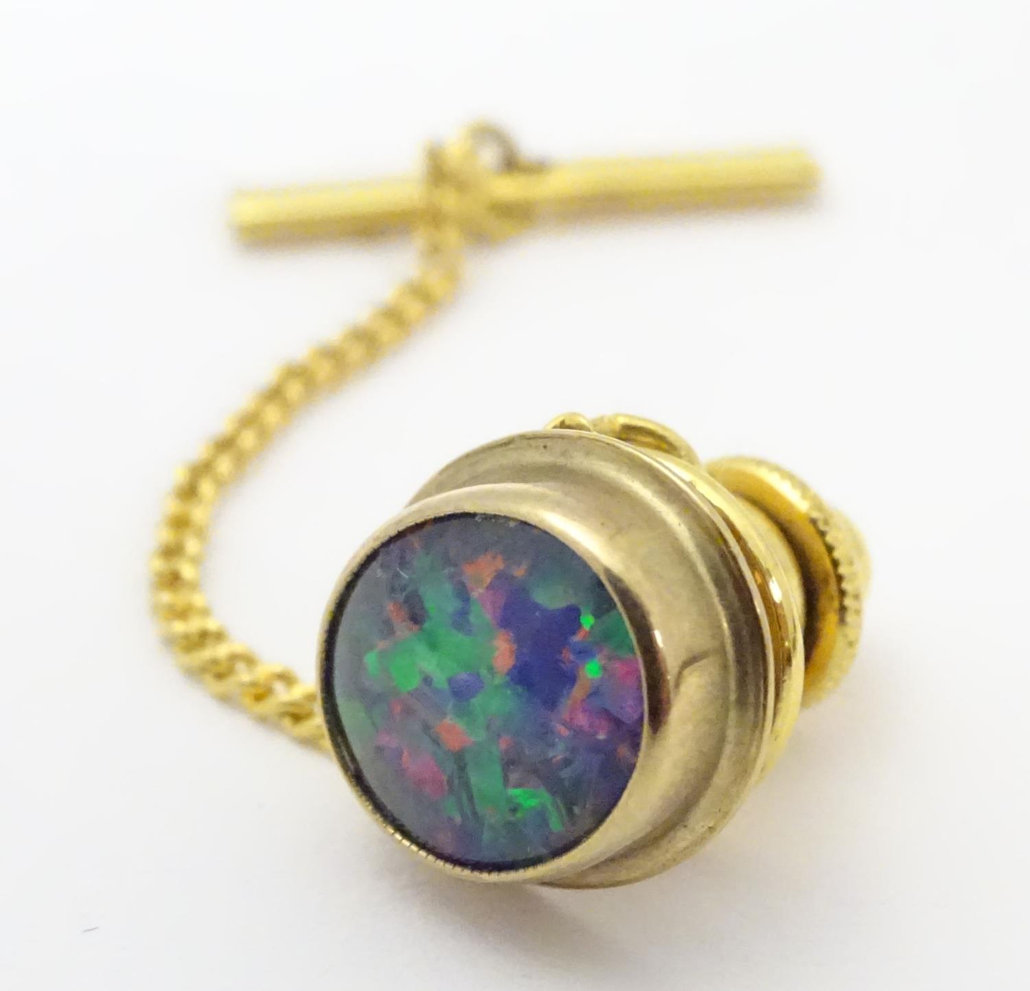 A 9 ct gold tie pin with central opalesque stone and yellow metal securer. Please Note - we do not