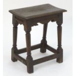 A 17thC oak peg jointed stool with a rectangular top, carved shaped aprons above turned tapering