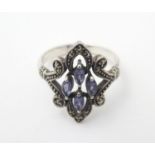 A silver dress ring set with amethysts and marcasite detail. Ring size approx S Please Note - we