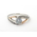 A silver ring with 9ct gold detail set with central white stone flanked by bands of chip set