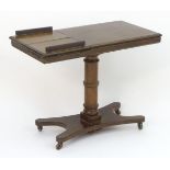 A Victorian mahogany reading table with an adjustable top, having reading / writing stands above a