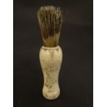 A 19thC bone shaving brush, with later scrimshaw decoration depicting crossed cannons with