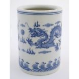 A Chinese blue and white cylindrical brush pot decorated with stylised dragons, clouds and flames.