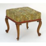 A 19thC walnut stool with squared upholstered top and raised on cabriole legs with french scrolled