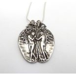 A silver pendant on chain, the pendant formed as an apple with a depiction of Adam and Eve.