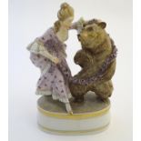 A Copenhagen style figural group with a woman dancing with a bear with a garland of flowers.