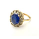 A 9ct gold ring set with central oval facet cut blue stone bordered by 12 white stones. The